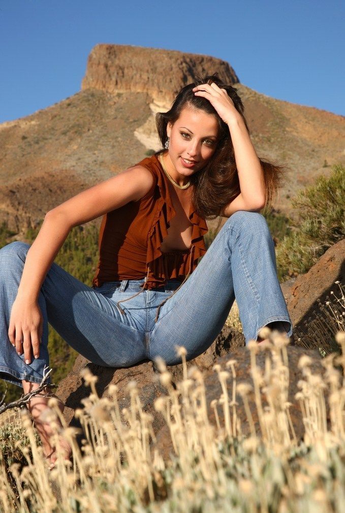 young brunette girl undresses a top and jeans on the mountains