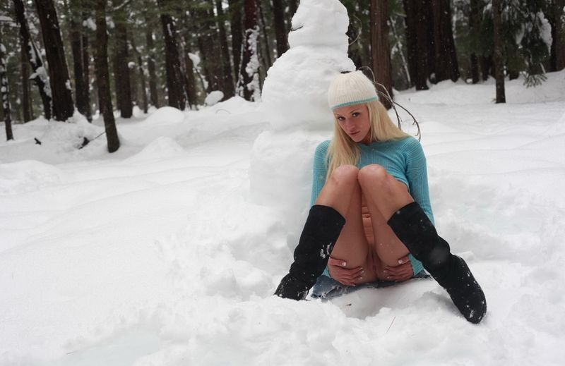 young blonde girl with a snowman outside in the winter