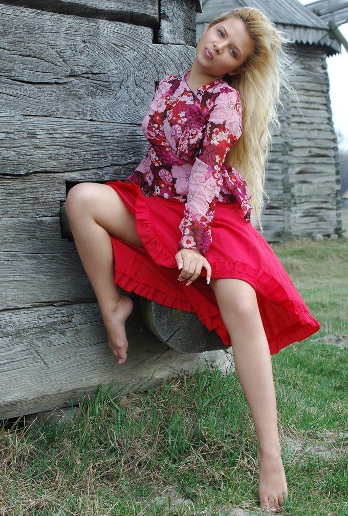 young curly blonde girl wearing a red dress in the village