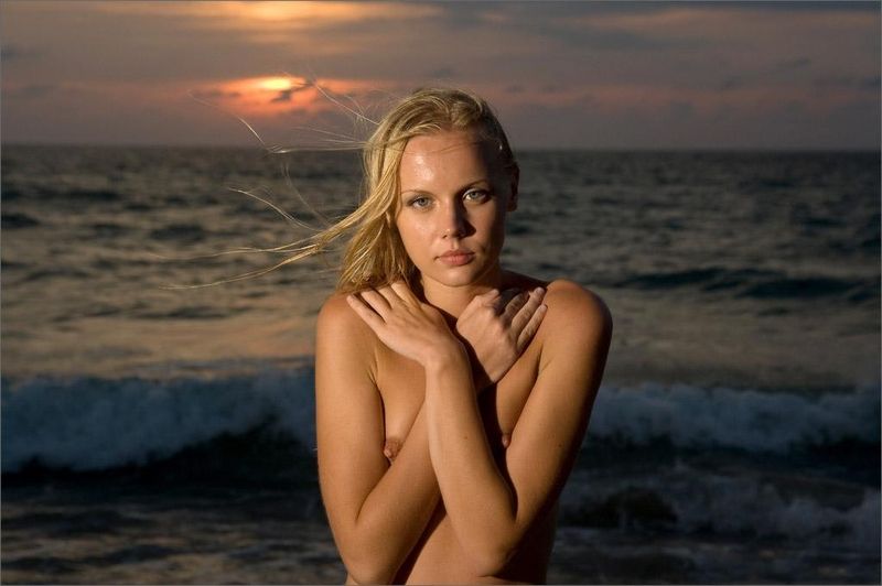 young blonde girl in the sea at sunset