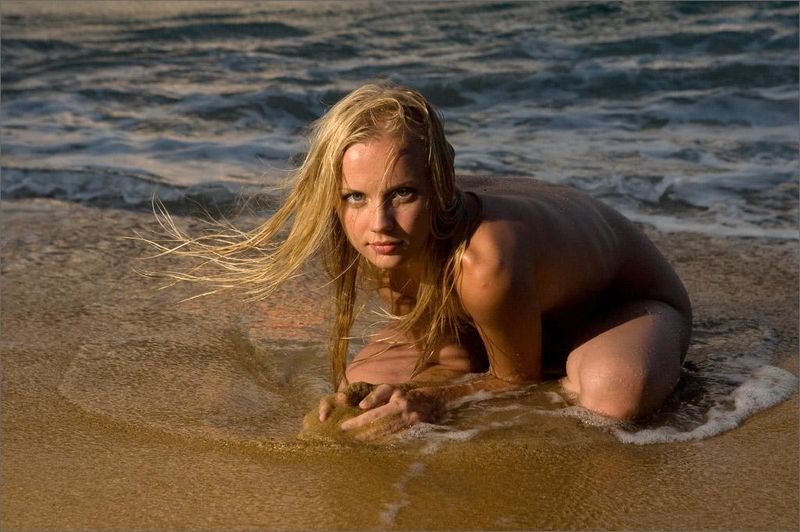 young blonde girl in the sea at sunset