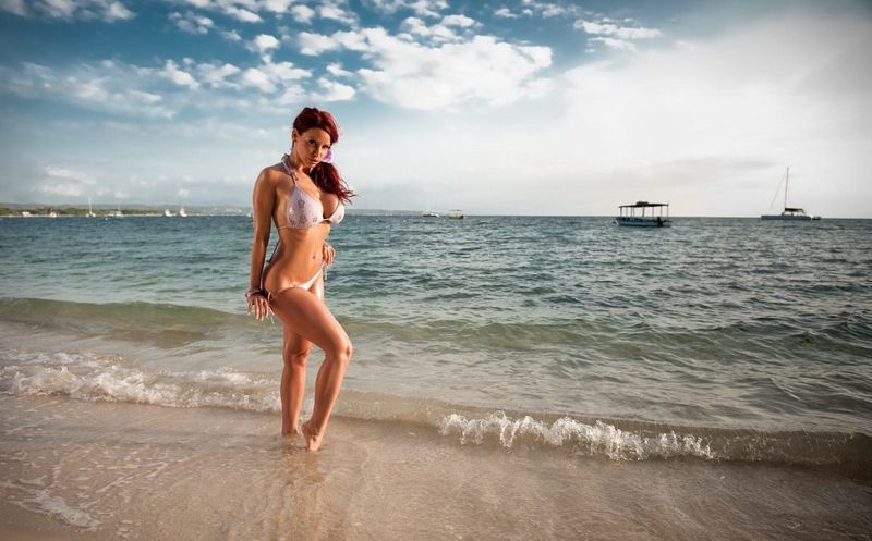 red haired girl strips her swimsuit in the sea