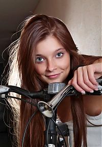 Babes: cute young brunette girl with long hair and blue eyes posing near the bicycle