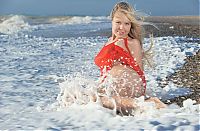 Babes: blonde girl reveals her red chemise on the beach in the sea
