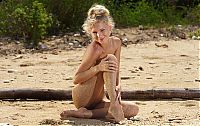 Nake.Me search results: young blonde girl posing on the sandy beach with driftwood and remains of trees
