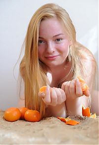 Babes: young reddish blonde girl posing on the old couch while eating mandarins