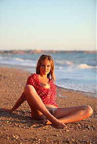Babes: young blonde girl reveals her red blouse with white dots on the beach at the sea