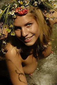 Babes: blonde girl with a floral wreath outside in the nature at the waterfall